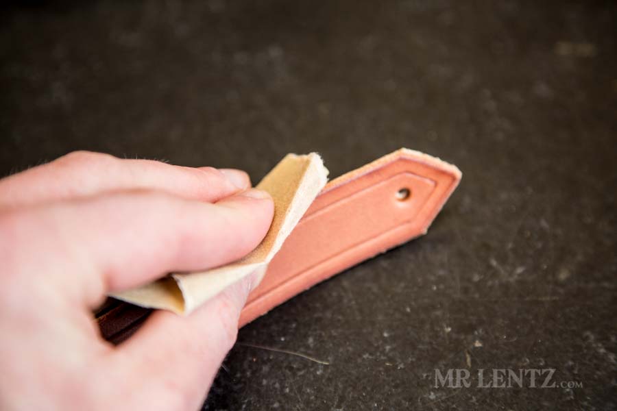 sanding the edges on retaining strap for axe sheath