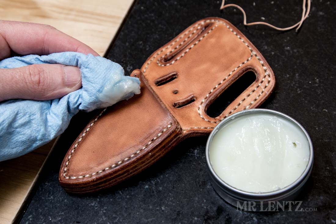 applying natural conditioner with beeswax to knife sheath