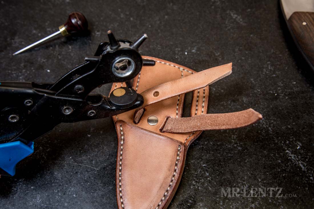 punching hole in retaining strap on sheath